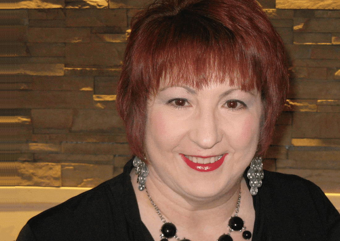 A woman with red hair and black shirt smiling.
