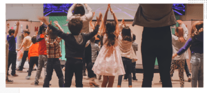 A group of children holding hands in the air.