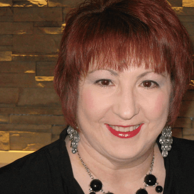 A woman with red hair and black shirt smiling.